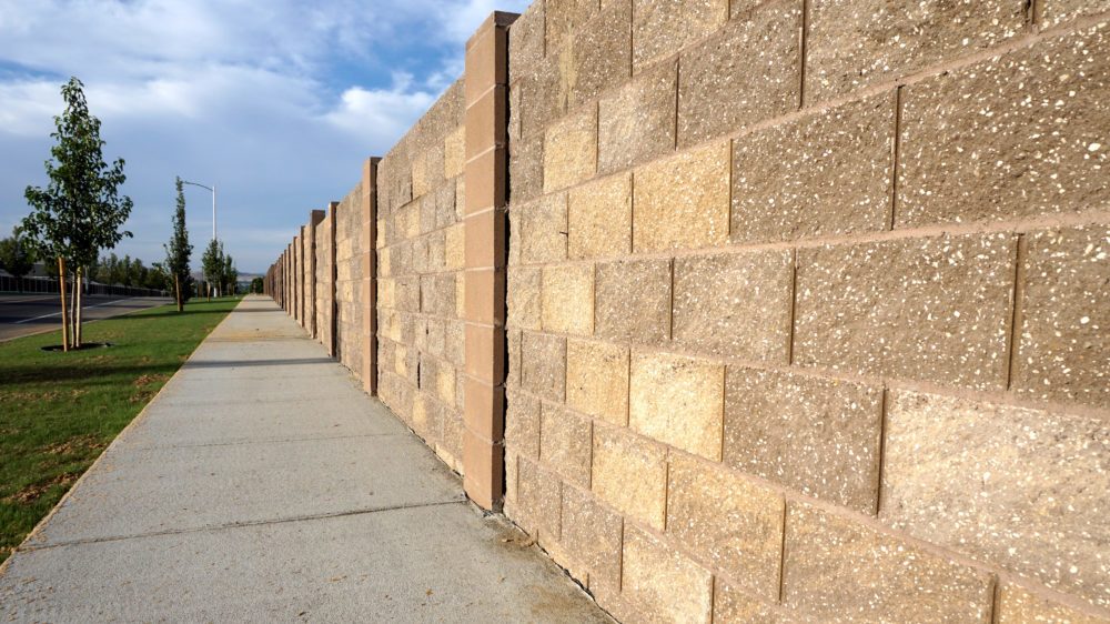Stone block sound barrier built in neighborhood to block road noise.