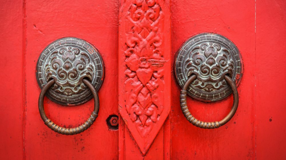 Vintage brass cabinet hardware on a red decorative door.