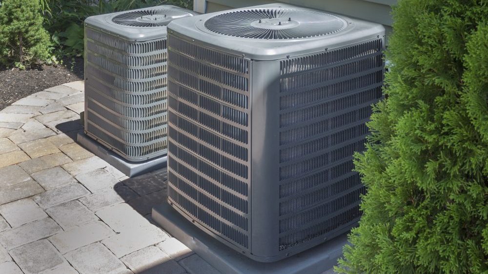 HVAC heating and air-conditioner units along side a home with screening landscape.