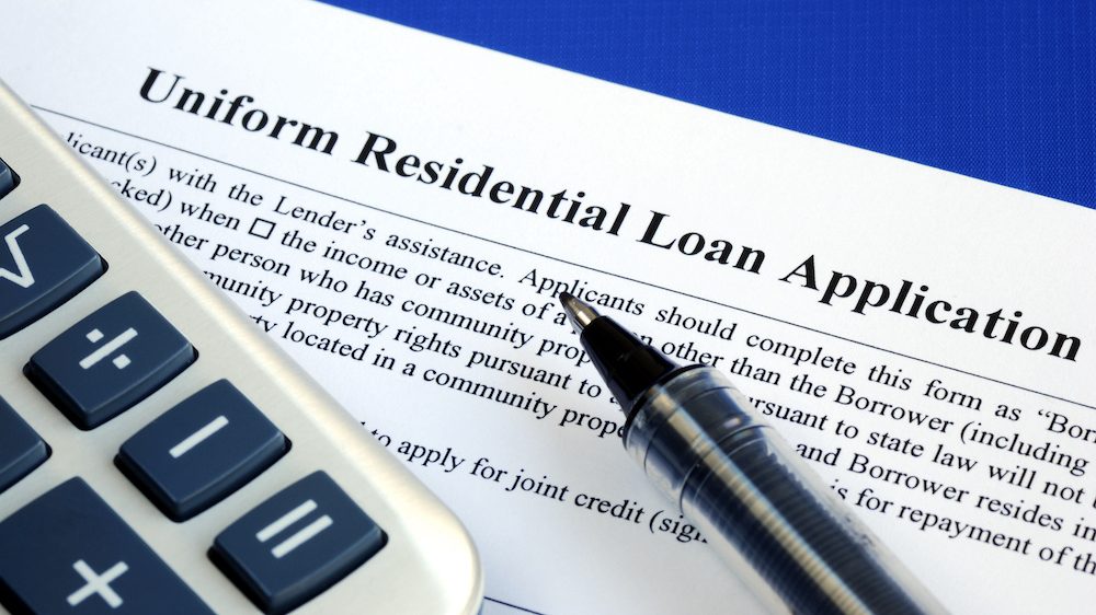 A mortgage loan application isolated on a blue background with a pen and a calculator.