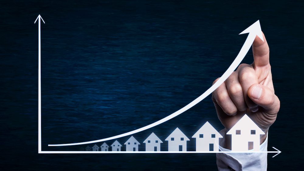 Business hand touching on a real estate of soaring sales with low housing inventory.