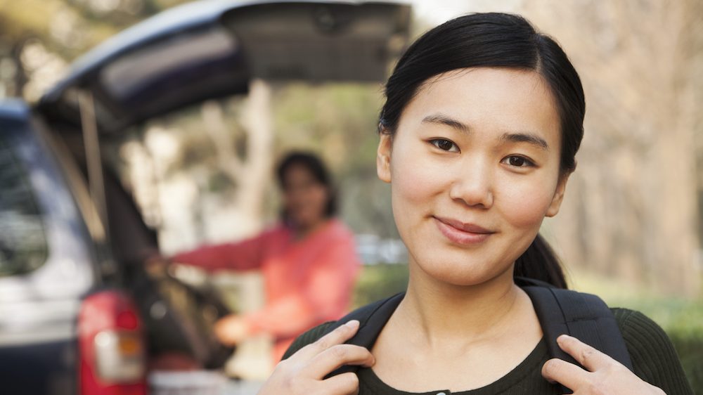 Portrait of girl in front of car on college move-in day.