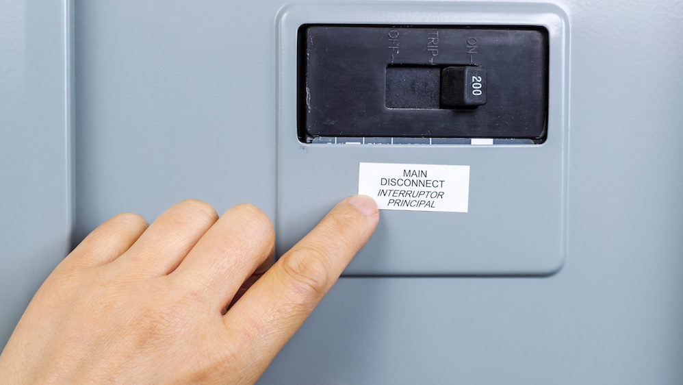 Female hand near main circuit breaker of house power panel shutting of the utilities.