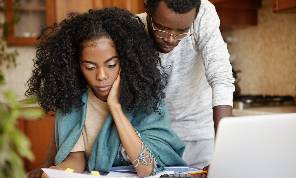 Stressed African couple concerned about home prices increasing while looking for a new house to purchase.