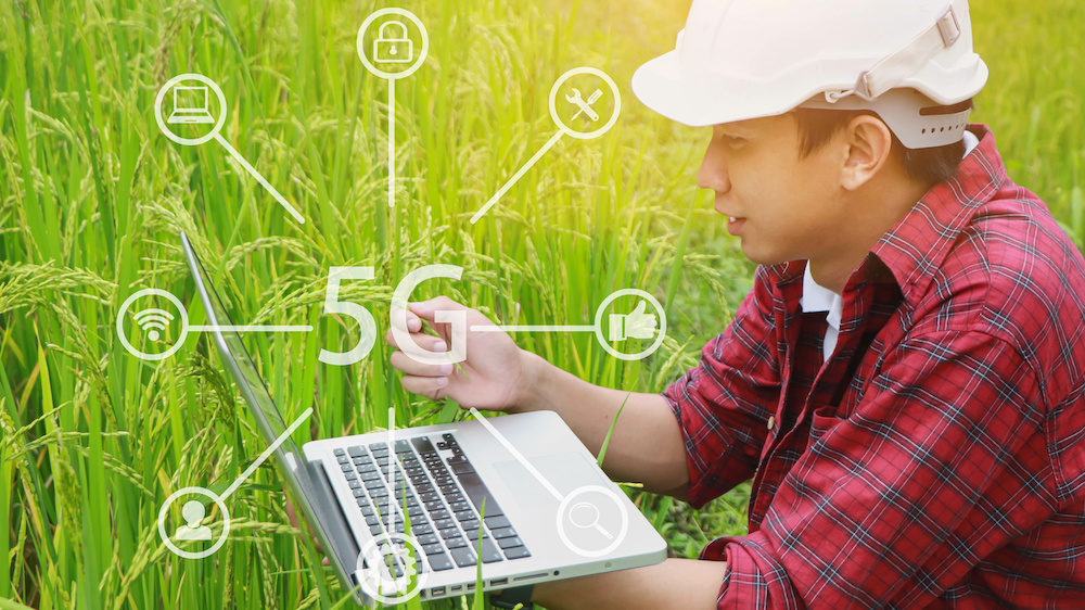 Farmer on rural land connecting to satellite internet service on his laptop in his field.