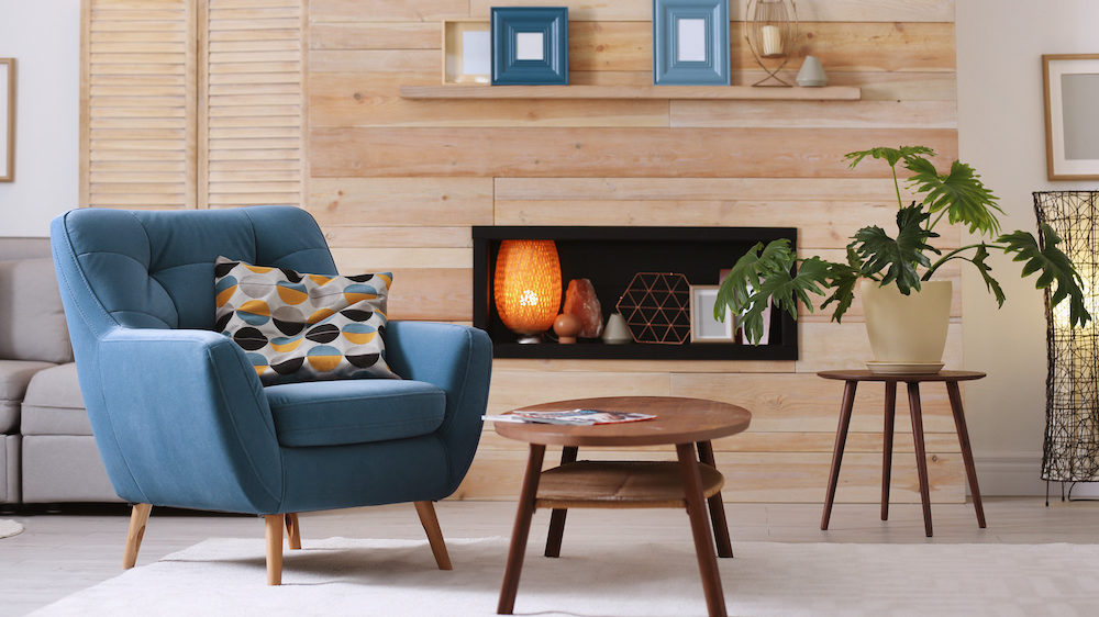 Cozy apartment with rental furniture. There is a blue armchair and coffee table in the foreground.