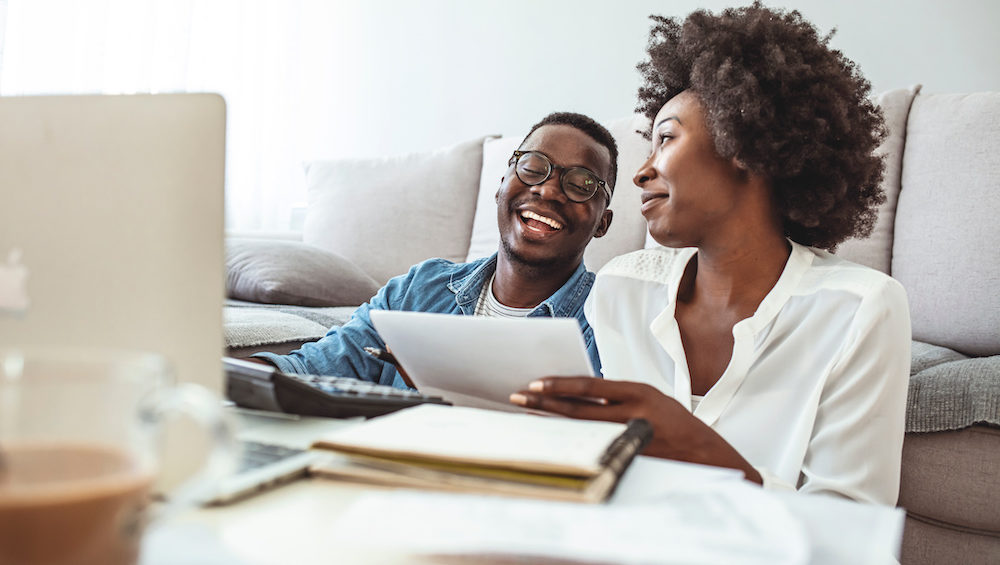 Young married couple doing their paperwork together and analyzing their changing insurance needs on their laptop.