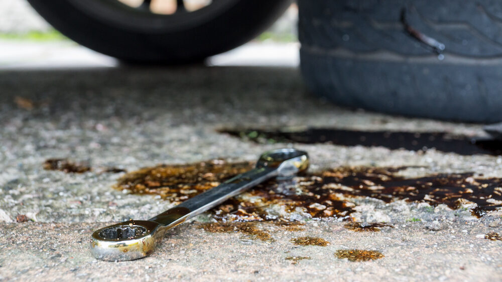 A socket wrench was left on the floor in a puddle of oil stains.